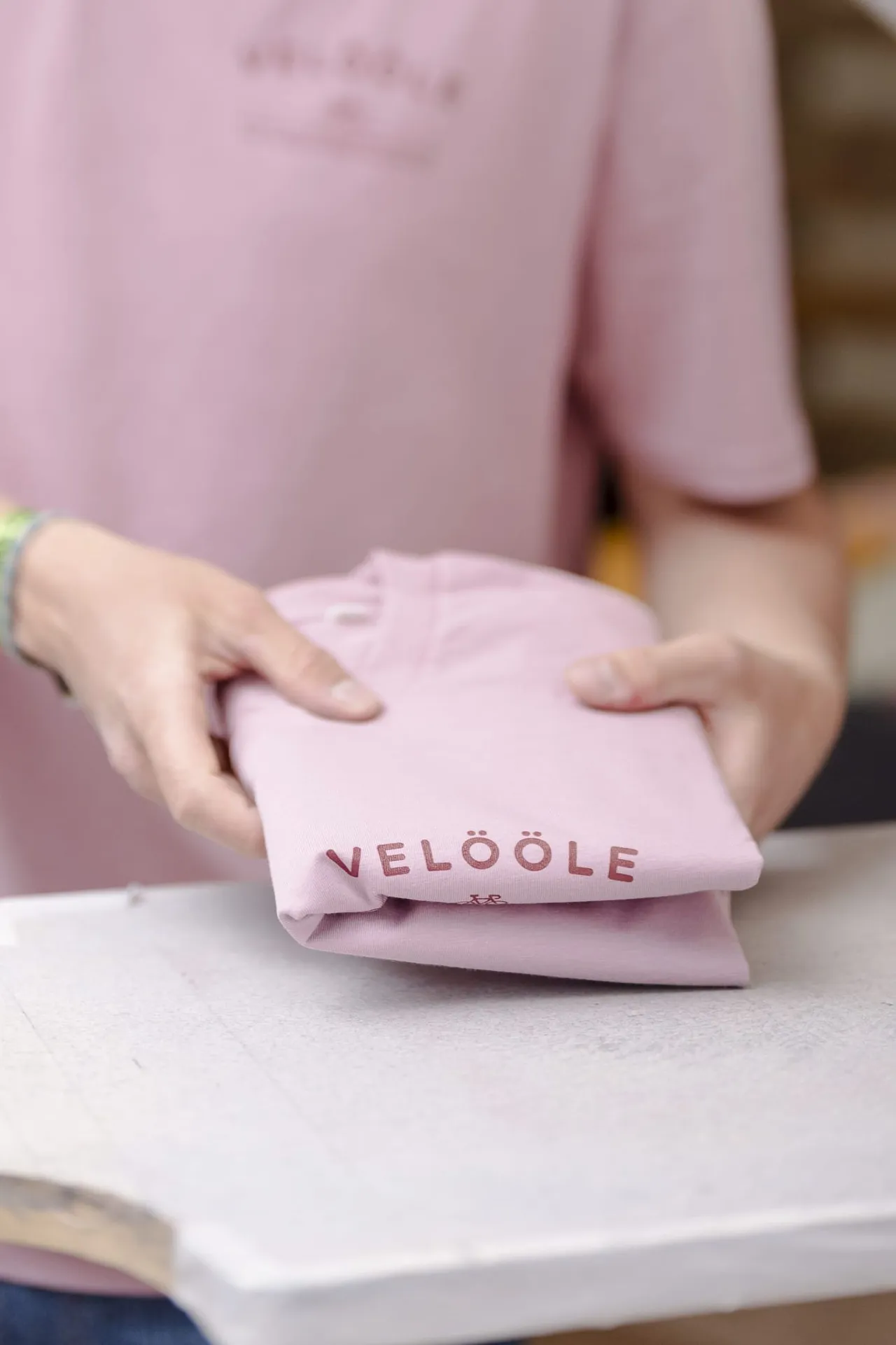 Hände falten ein frisch bedrucktes rosa Shirt mit «Velööle»-Aufdruck