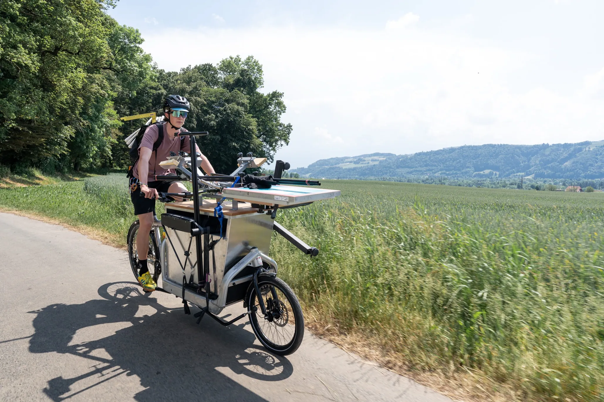 Druckvelo-Team fährt mit dem Lastenvelo und der mobilen Siebdruckerei über Land